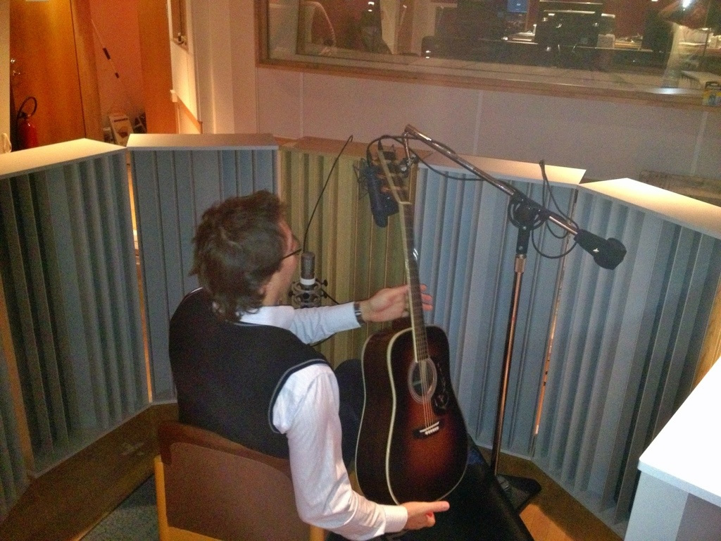 Janke Jönsson med akustisk gitarr under inspelning i inspelningsstudio